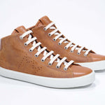 Vue de trois quarts de l'avant de la chaussure de sport rouille sneaker avec une tige en daim, un logo perforé, une fermeture éclair interne et une semelle blanche.