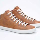 Vue de trois quarts de l'avant de la chaussure de sport rouille sneaker avec une tige en daim, un logo perforé, une fermeture éclair interne et une semelle blanche.