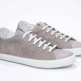 Vue de trois quarts de l'avant de la chaussure beige sneaker avec le logo perforé de la couronne sur l'empeigne. Tige en daim et semelle en caoutchouc blanc.