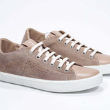 Vue de trois quarts avant de la chaussure basse cuoio sneaker avec le logo perforé de la couronne sur la tige. Tige en daim et semelle en caoutchouc blanc.