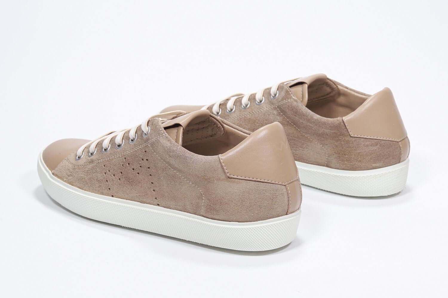 Vue de trois quarts arrière de la chaussure basse cuoio sneaker avec le logo perforé de la couronne sur l'empeigne. Tige en daim et semelle en caoutchouc blanc.