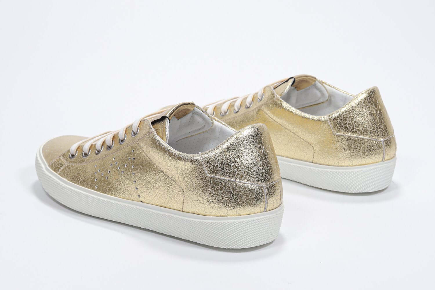 Dreiviertelansicht der Rückseite des goldenen Low Top sneaker mit perforiertem Kronenlogo auf dem Obermaterial. Obermaterial aus Metallic-Leder und weiße Gummisohle.