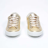 Vorderansicht des goldenen Low Top sneaker mit perforiertem Kronenlogo auf dem Obermaterial. Obermaterial aus Metallic-Leder und weiße Gummisohle.