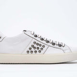 Profil latéral de la chaussure blanche sneaker. Tige en cuir avec clous et semelle en caoutchouc vintage.