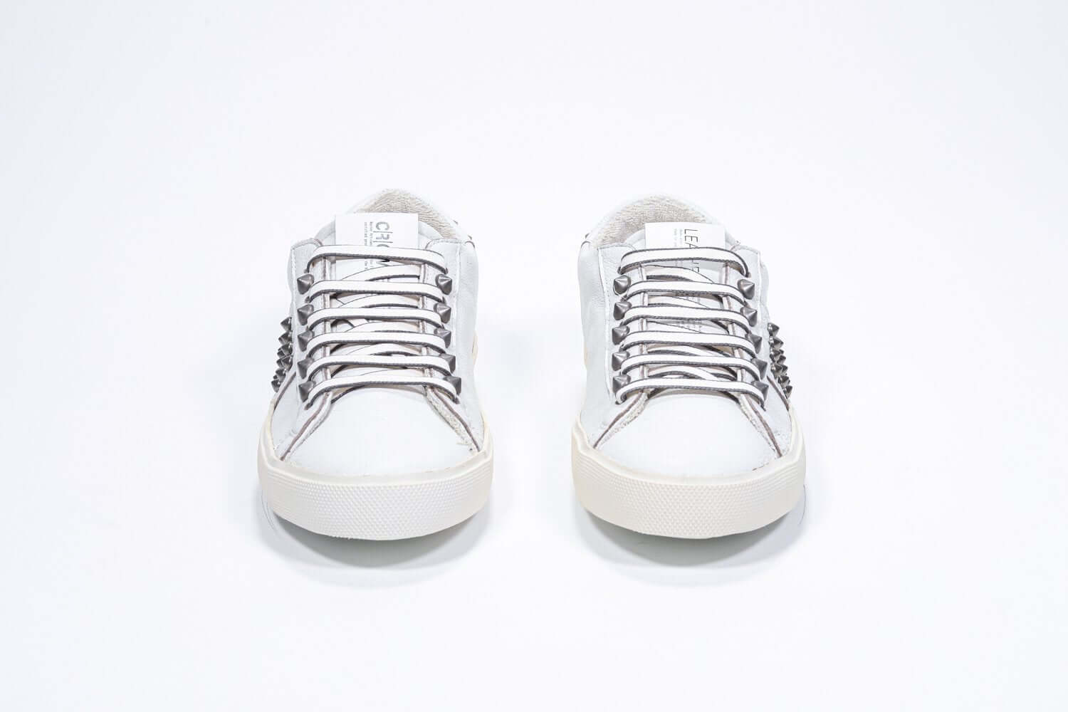 Vue de face de la chaussure blanche sneaker. Tige en cuir avec clous et semelle en caoutchouc vintage.