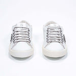 Vue de face de la chaussure blanche sneaker. Tige en cuir avec clous et semelle en caoutchouc vintage.