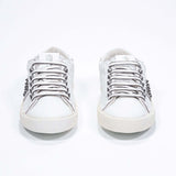 Vue de face de la chaussure blanche sneaker. Tige en cuir avec clous et semelle en caoutchouc vintage.
