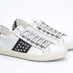 Tre quarti di BASSE vista frontale in bianco e nero sneaker. Tomaia in pelle con borchie e suola in gomma vintage.