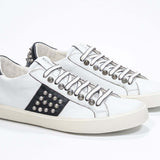 Tre quarti di BASSE vista frontale in bianco e nero sneaker. Tomaia in pelle con borchie e suola in gomma vintage.
