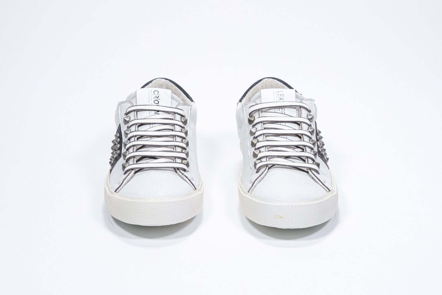 Vista frontale di BASSE bianco e nero sneaker. Tomaia in pelle con borchie e suola in gomma vintage.