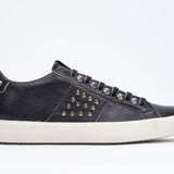 Profilo laterale di BASSE nero sneaker. Tomaia in pelle con borchie e suola in gomma anticata.