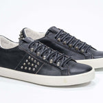 Tre quarti di BASSE nero sneaker. Tomaia in pelle con borchie e suola in gomma anticata.
