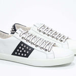 Tre quarti di BASSE vista frontale in bianco e nero sneaker. Tomaia in pelle con borchie e suola in gomma bianca.