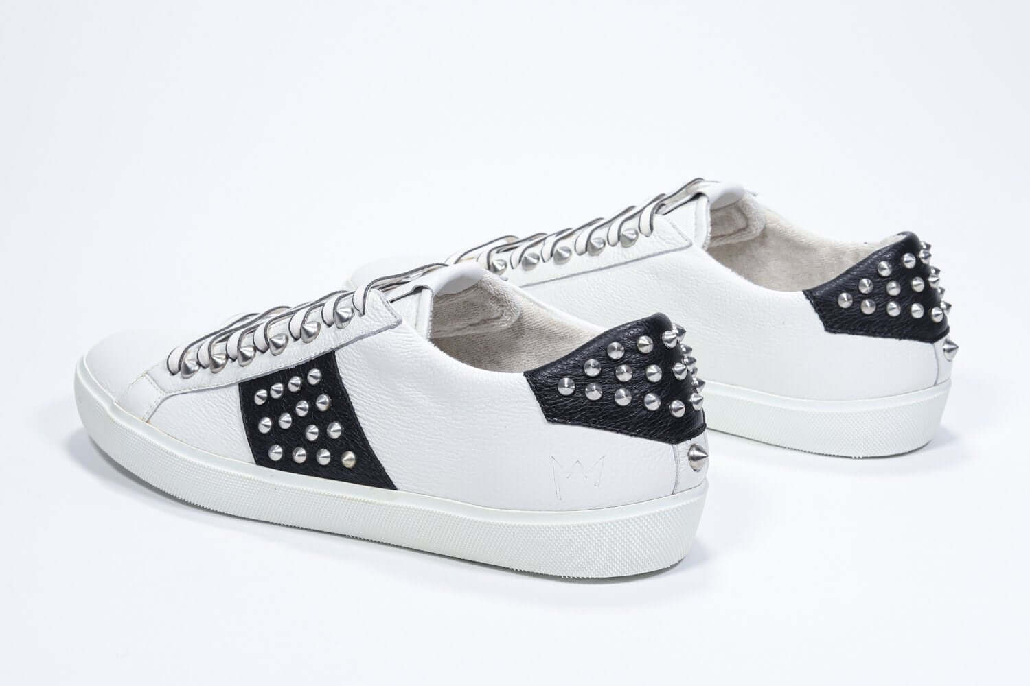 Tre quarti posteriore di BASSE bianco e nero sneaker. Tomaia in pelle con borchie e suola in gomma bianca.