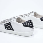 Tre quarti posteriore di BASSE bianco e nero sneaker. Tomaia in pelle con borchie e suola in gomma bianca.