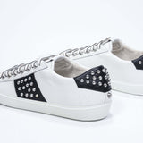 Tre quarti posteriore di BASSE bianco e nero sneaker. Tomaia in pelle con borchie e suola in gomma bianca.