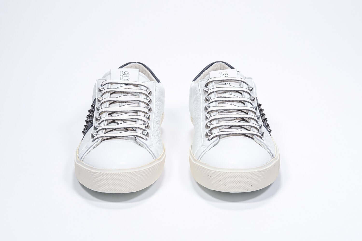 Vista frontale di BASSE bianco e nero sneaker. Tomaia in pelle con borchie e suola in gomma bianca.