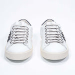 Vista frontale di BASSE bianco e nero sneaker. Tomaia in pelle con borchie e suola in gomma bianca.