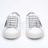 Vista frontale di BASSE bianco e nero sneaker. Tomaia in pelle con borchie e suola in gomma bianca.