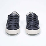 Vue de face de la chaussure noire sneaker. Tige en cuir avec clous et semelle en caoutchouc vintage.