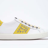 Seitliches Profil des weißen und gelben Low Top sneaker. Obermaterial aus Vollleder mit Nieten und weißer Gummisohle.