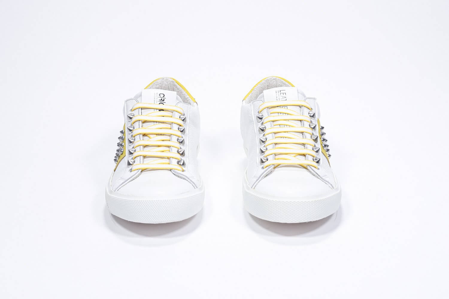 Vorderansicht des weißen und gelben Low Top sneaker. Obermaterial aus Vollleder mit Nieten und weißer Gummisohle.