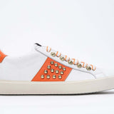 Profilo laterale di BASSE bianco e arancione sneaker. Tomaia in pelle con borchie e suola in gomma vintage.
