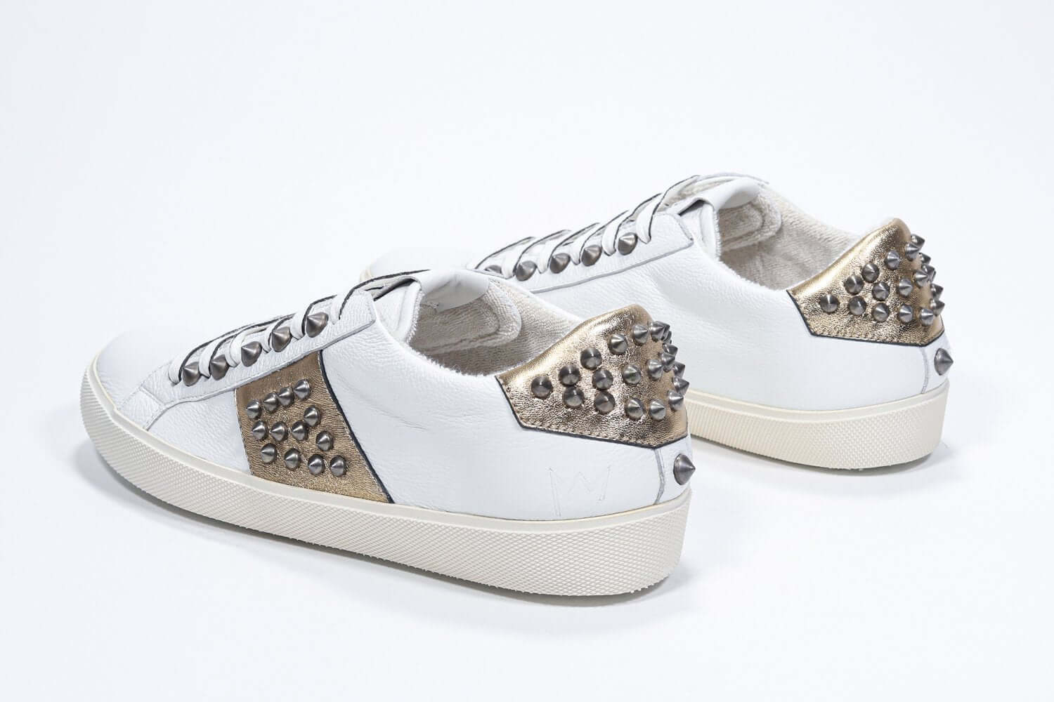 Dreiviertelansicht der Rückseite von Low Top Weiß und Metallic Gold sneaker. Obermaterial aus Vollleder mit Nieten und Vintage-Gummisohle.