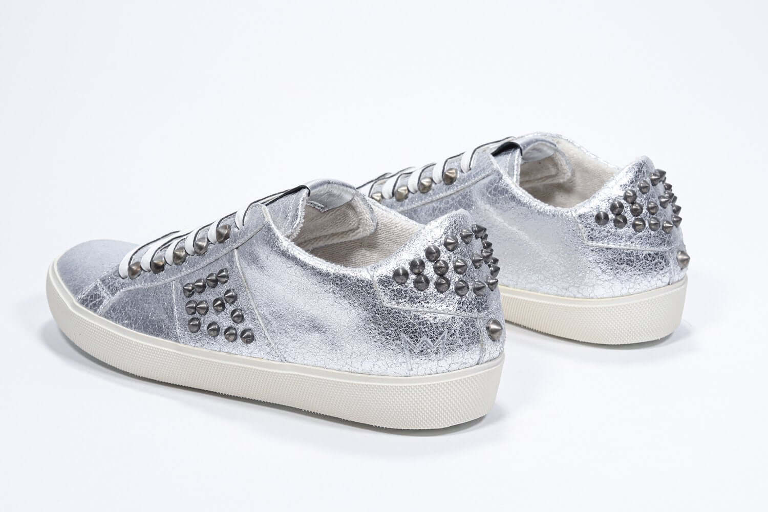 Vista posteriore di tre quarti di BASSE argento metallizzato sneaker. Tomaia in pelle con borchie e suola in gomma vintage.