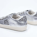 Vista posteriore di tre quarti di BASSE argento metallizzato sneaker. Tomaia in pelle con borchie e suola in gomma vintage.