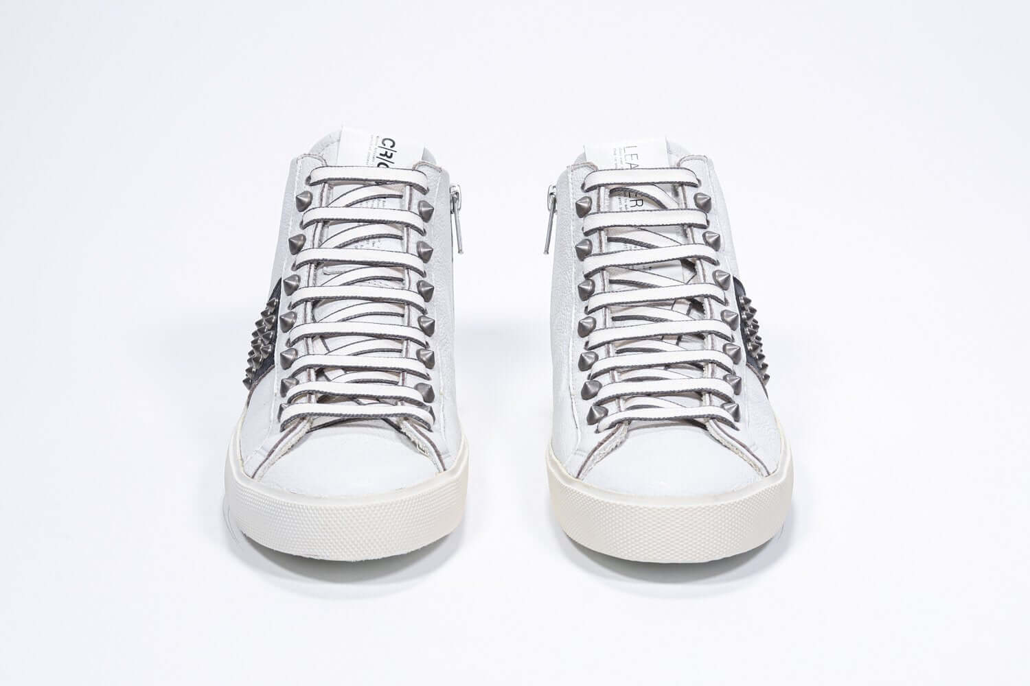 Vorderansicht von Mid Top weiß und schwarz sneaker. Obermaterial aus Vollleder mit Nieten, einem internen Reißverschluss und einer Vintage-Gummisohle.