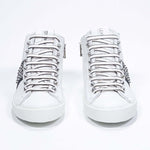 Vista frontale della mid top bianca e nera sneaker. Tomaia in pelle con borchie, zip interna e suola in gomma bianca.