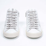 Front view of mid top white sneaker. Full leather upper with studs, an internal zip and vintage rubber sole.