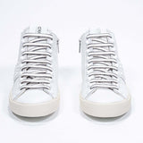 Front view of mid top white sneaker. Full leather upper with studs, an internal zip and vintage rubber sole.