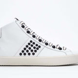 Side profile of mid top white sneaker. Full leather upper with studs, an internal zip and vintage rubber sole.