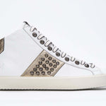 Profil latéral d'un mid top blanc et or métallisé sneaker. Tige en cuir avec clous, fermeture à glissière intérieure et semelle en caoutchouc vintage.