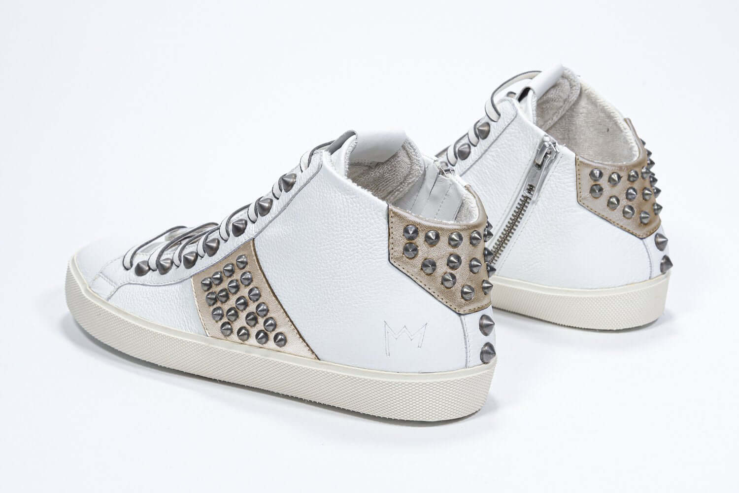 Vue de trois quarts arrière d'un modèle intermédiaire blanc et or métallisé sneaker. Tige en cuir avec clous, fermeture à glissière interne et semelle en caoutchouc vintage.