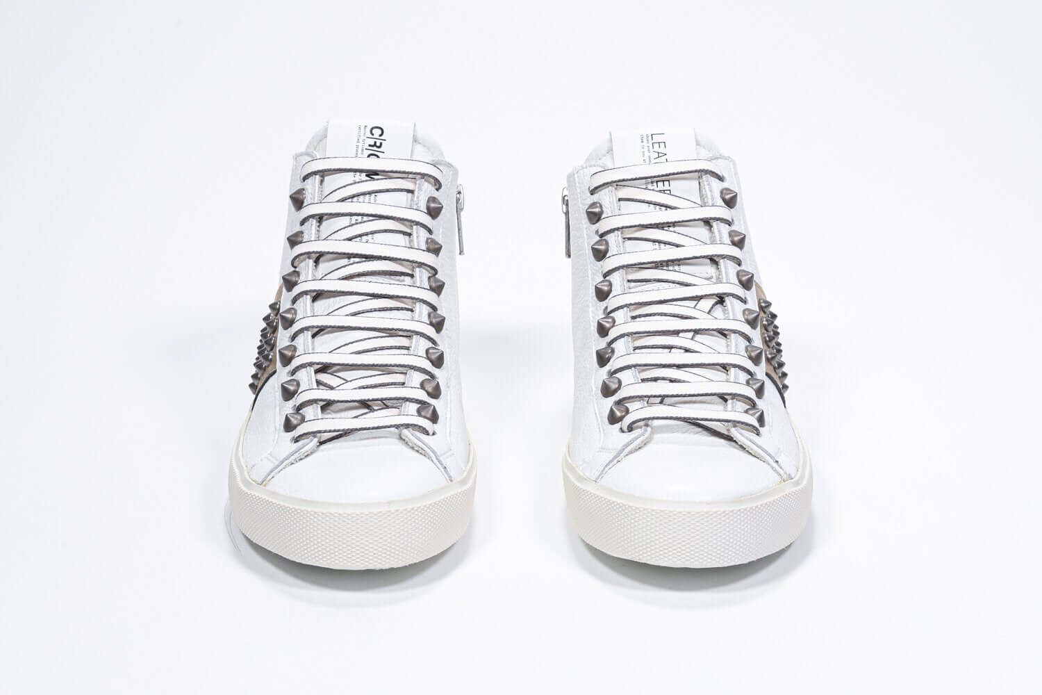 Vue de face d'un modèle intermédiaire blanc et or métallisé sneaker. Tige en cuir avec clous, fermeture à glissière intérieure et semelle en caoutchouc vintage.