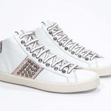 Tre quarti di mid top bianco e rosa metallizzato sneaker. Tomaia in pelle con borchie, zip interna e suola in gomma vintage.