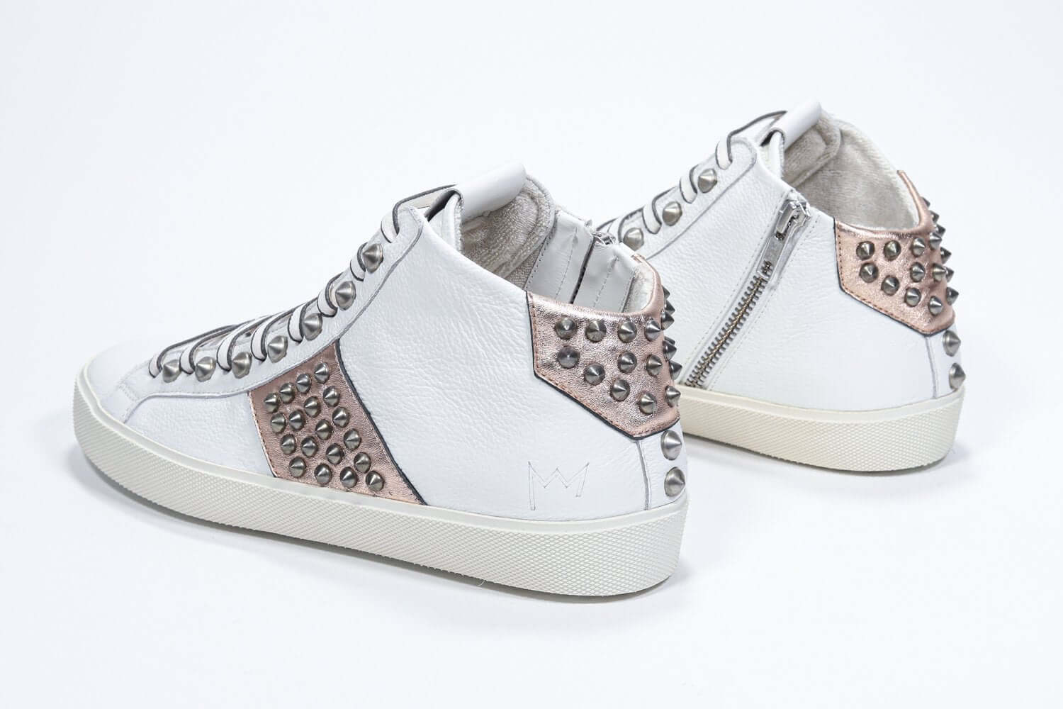 Vista posteriore di tre quarti di una mid top bianca e rosa metallizzata sneaker. Tomaia in pelle con borchie, zip interna e suola in gomma vintage.