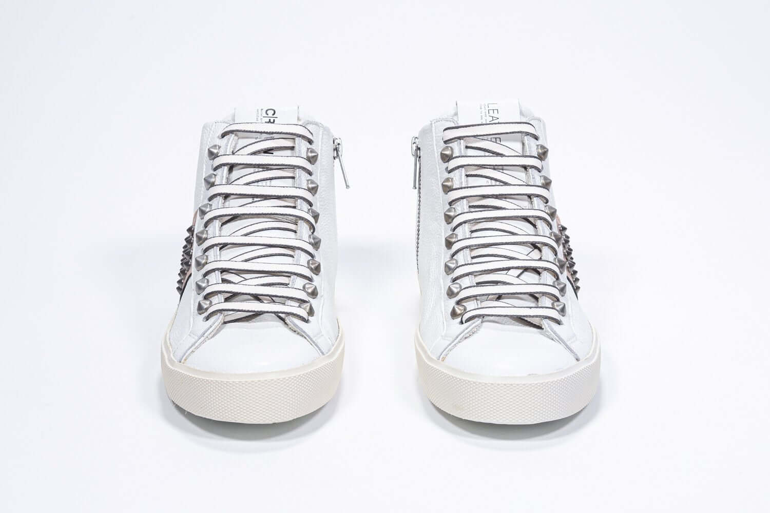 Vista frontale della mid top bianca e rosa metallizzata sneaker. Tomaia in pelle con borchie, zip interna e suola in gomma vintage.