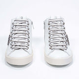 Vista frontale della mid top bianca e rosa metallizzata sneaker. Tomaia in pelle con borchie, zip interna e suola in gomma vintage.