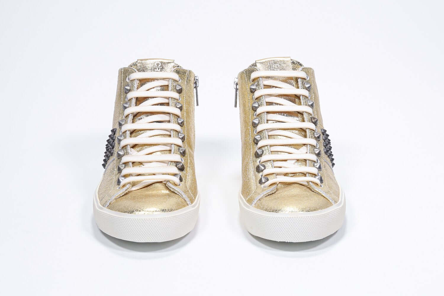 Vue de face de la chaussure intermédiaire en or métallisé sneaker. Tige en cuir avec clous, fermeture éclair intérieure et semelle en caoutchouc vintage.