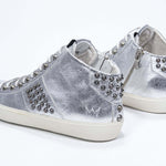 Dreiviertelansicht der Rückseite von Mid Top Metallic Silber sneaker. Obermaterial aus Vollleder mit Nieten, einem internen Reißverschluss und einer Vintage-Gummisohle.