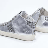 Dreiviertelansicht der Rückseite von Mid Top Metallic Silber sneaker. Obermaterial aus Vollleder mit Nieten, einem internen Reißverschluss und einer Vintage-Gummisohle.