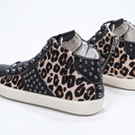 Vista posteriore di tre quarti del mid top leopardato sneaker. Tomaia in vitello e pelle con borchie, zip interna e suola in gomma vintage.