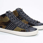 Three quarter front view of mid top camouflage print sneaker. Haircalf and leather upper with studs, an internal zip and vintage rubber sole.