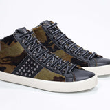 Three quarter front view of mid top camouflage print sneaker. Haircalf and leather upper with studs, an internal zip and vintage rubber sole.