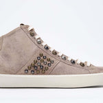 Profilo laterale di mid top color cuoio sneaker. Tomaia in pelle scamosciata con borchie, zip interna e suola in gomma vintage.