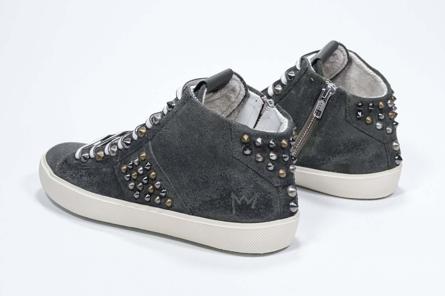 Three quarter back view of mid top khaki sneaker. Full suede upper with studs, an internal zip and vintage rubber sole.